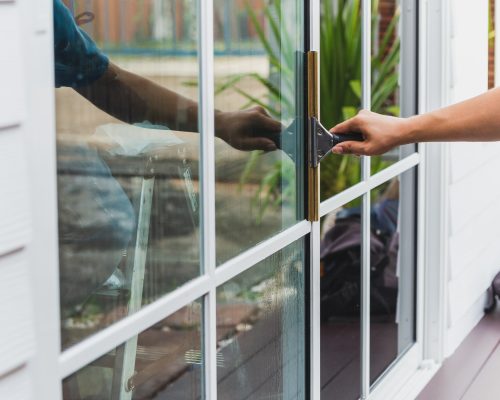 Worker use scraper cleaning window before installing tinting film.
